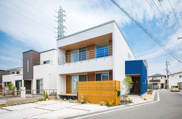 白の箱型のボリュームに玄関の青色のボリュームをつけた外観　